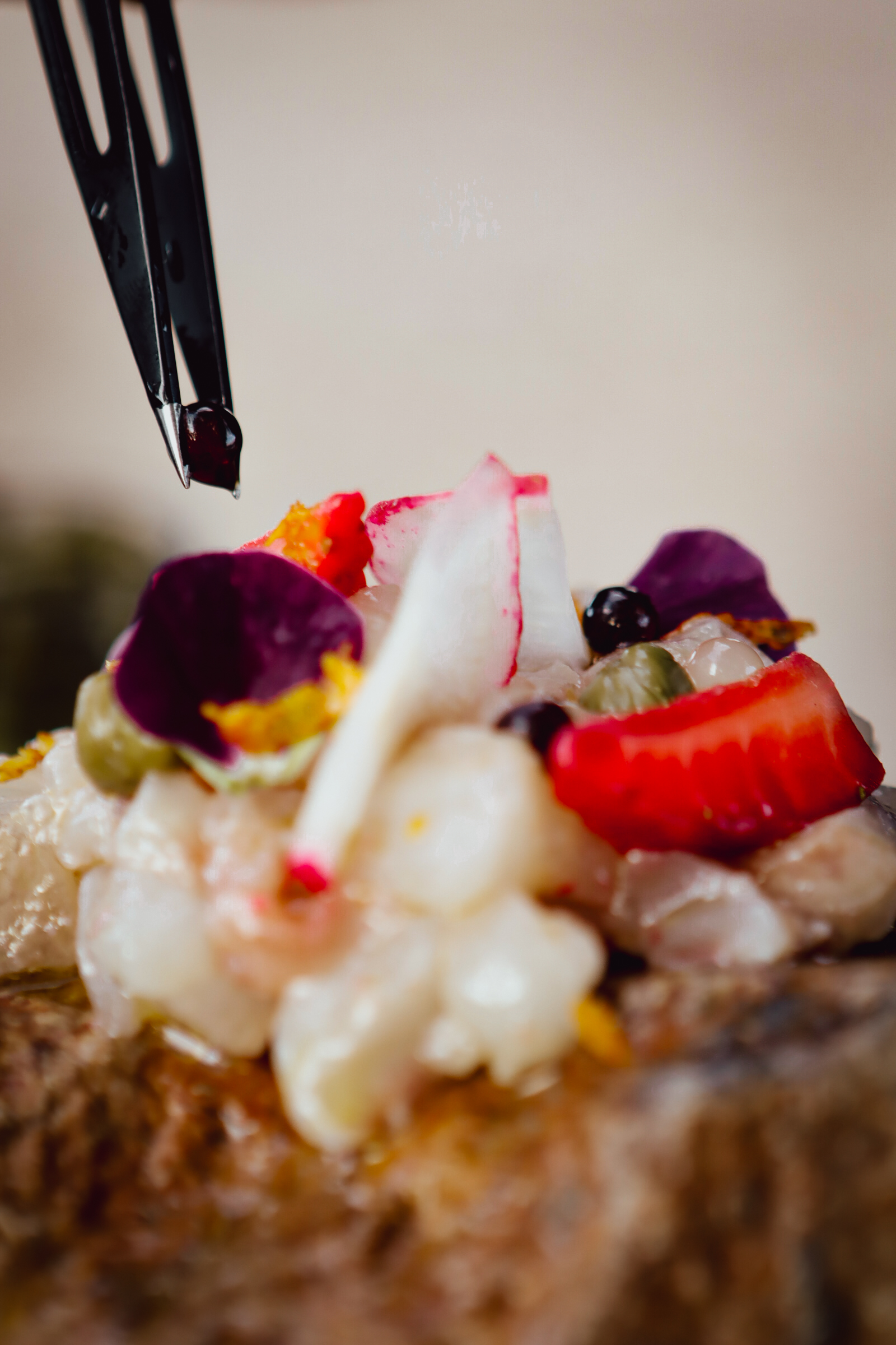 Chef placing a balsamic pearl with precision tweezers on a fine dining dish